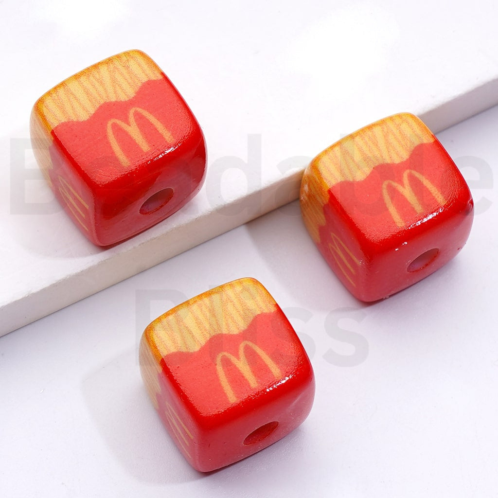 Three red and yellow dice-shaped beads on a white background