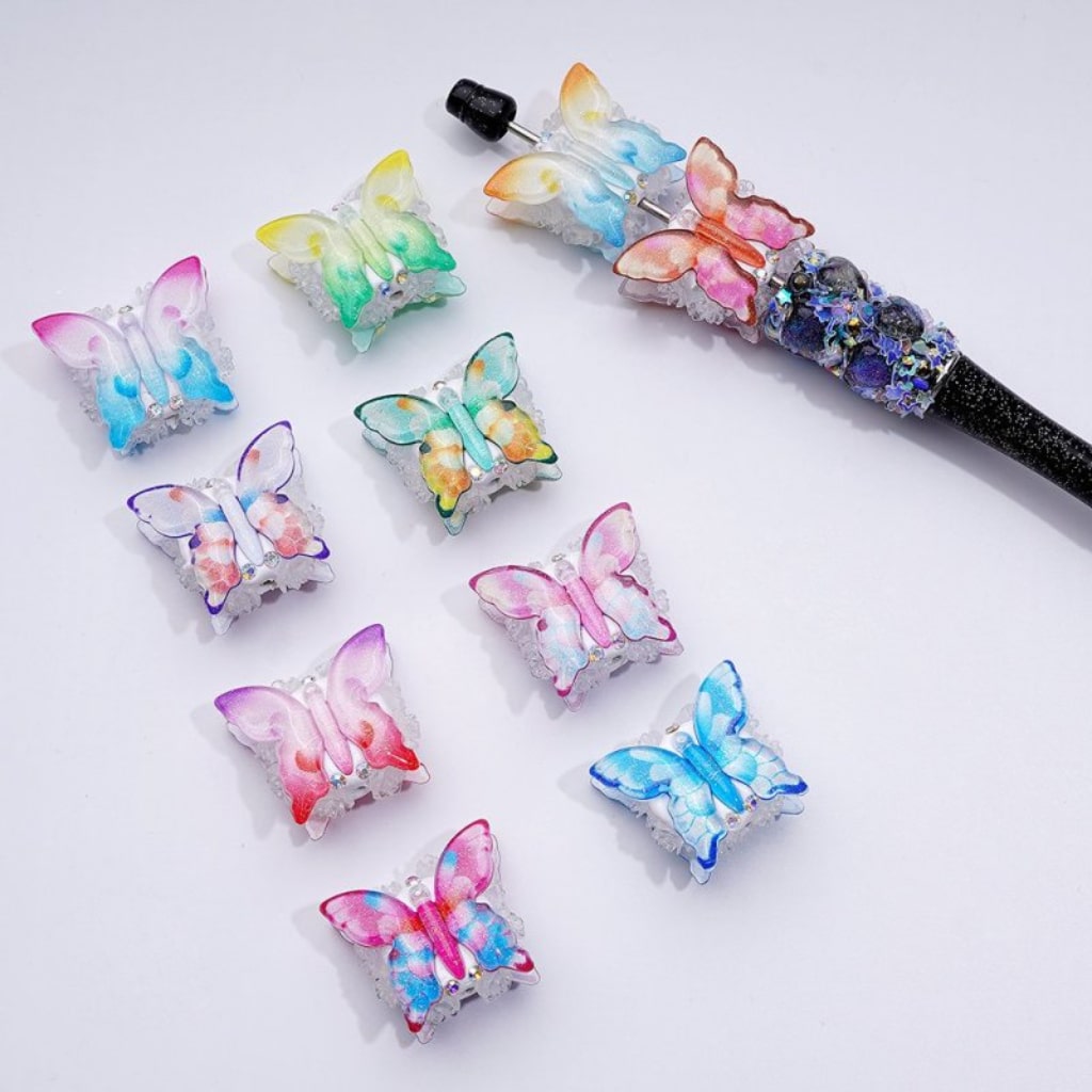 A collection of multicolored butterfly-shaped clay beads with AB crystals and transparent flowers, in various colors.
