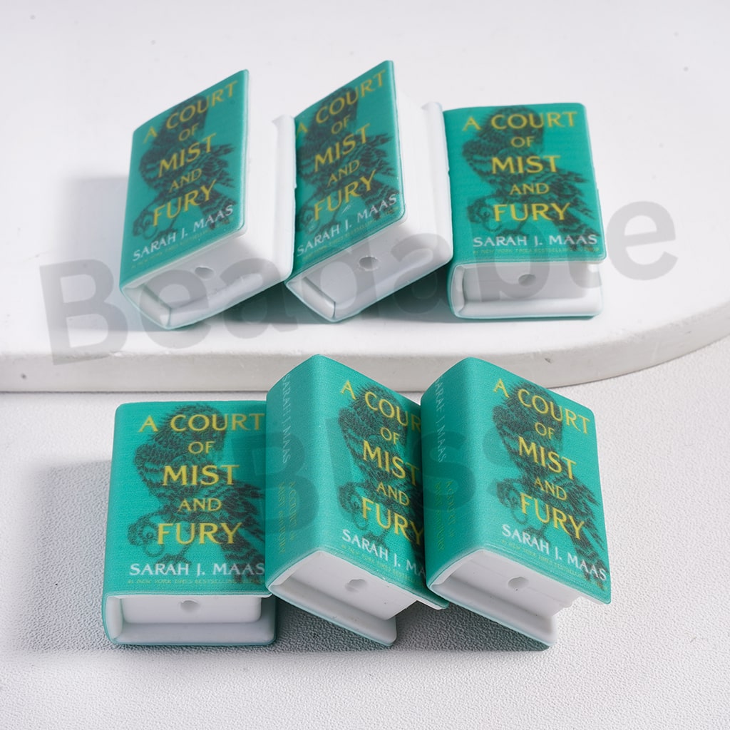 Five 'A Court of Mist and Fury' book-shaped candles on a white surface.