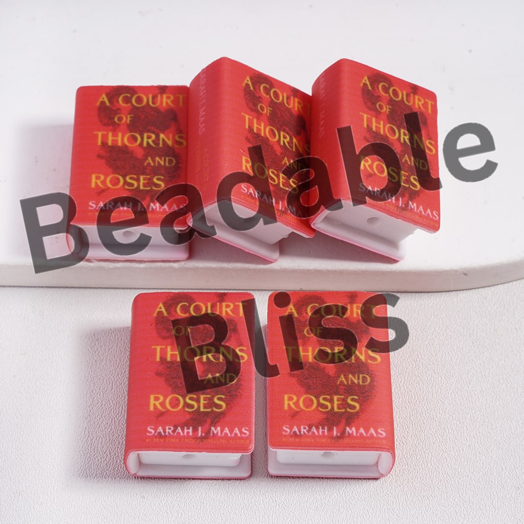 Red book titled 'A Court of Thorns and Roses' by Sarah J. Maas on a white surface.