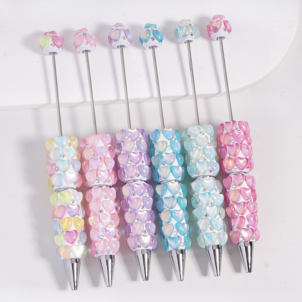 Set of colorful pens with heart-shaped designs on a white background