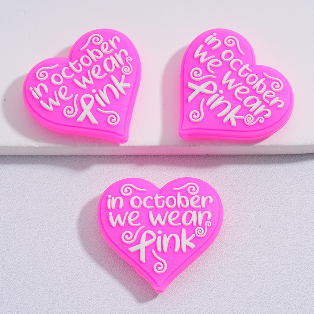 Three pink heart-shaped stickers with 'In October we wear pink' text on a white background