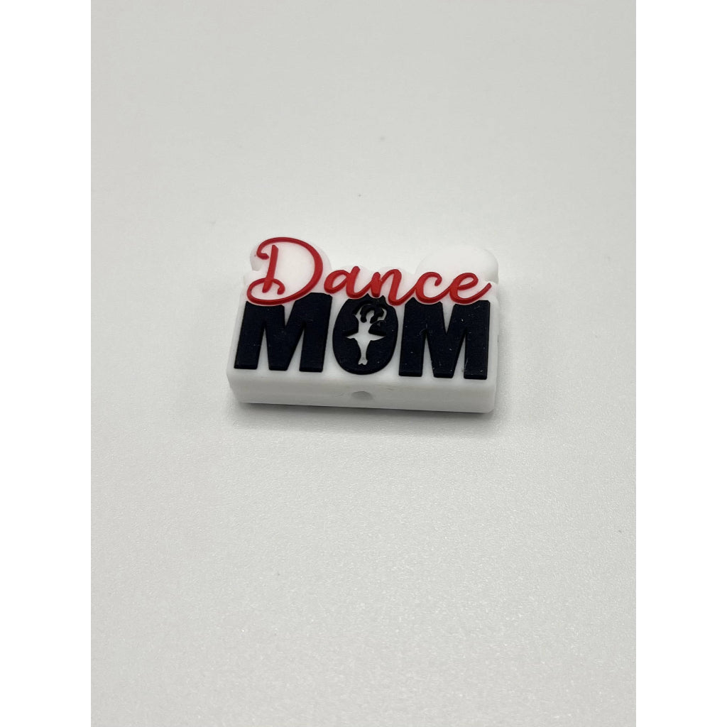 A white silicone bead with the text 'Dance Mom' in red and black.