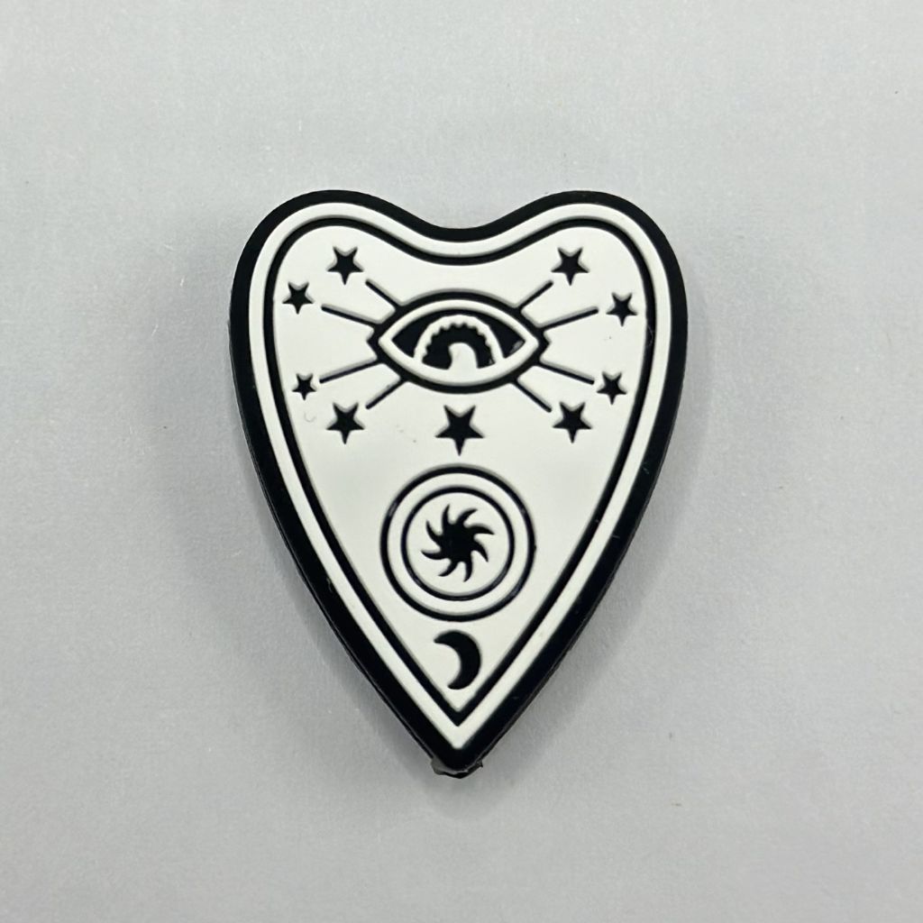 A silicone bead featuring a black star and moon with white heart shaped eyes, set against a white background.