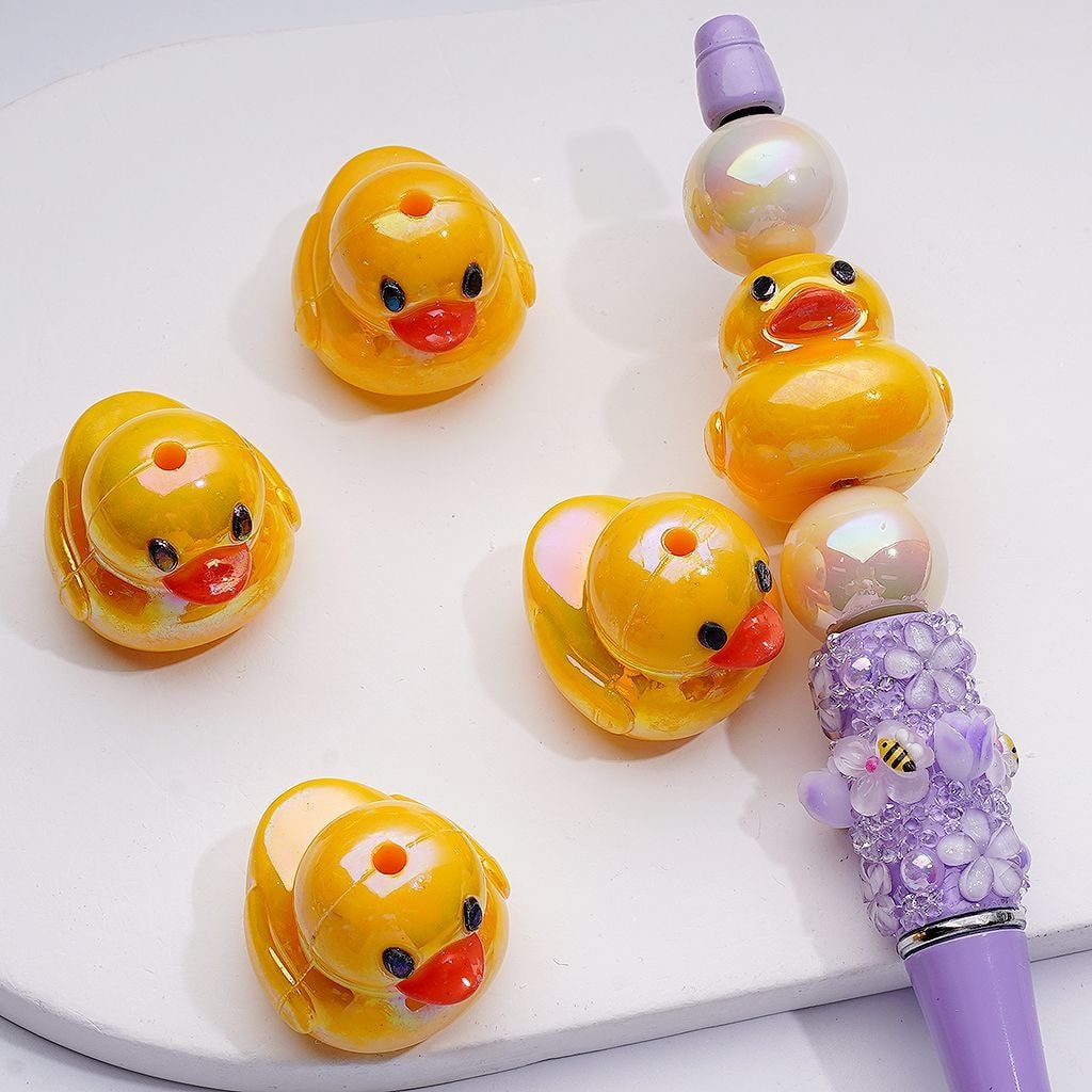 Set of yellow duck-shaped clips with a purple handle on a white background