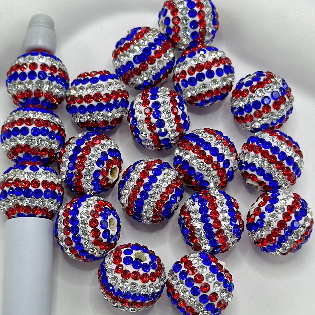 White round clay beads with a pattern of red and blue rhinestones, intended for use in arts and crafts.