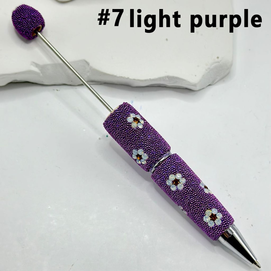 Decorative pen with beaded design on a light background

