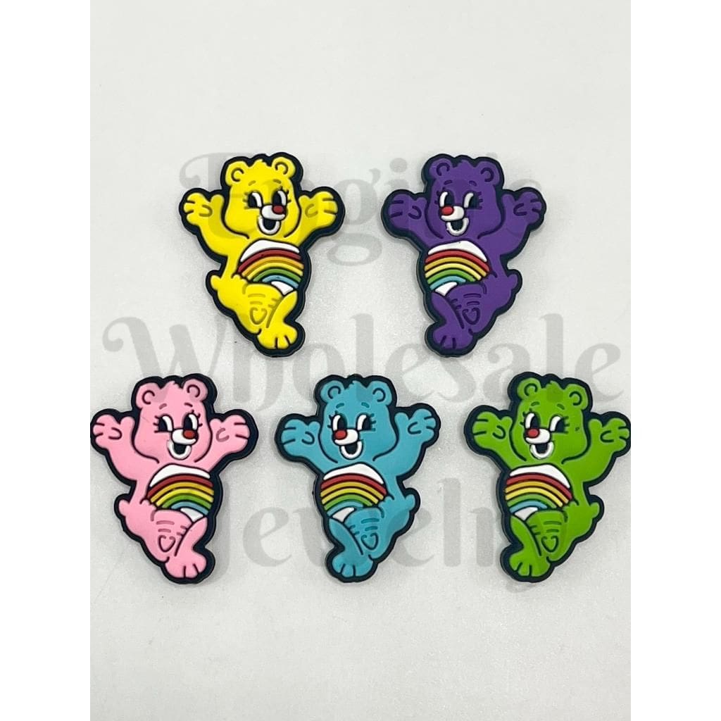 Five colorful cartoon bear pins with rainbow designs on a white background.

