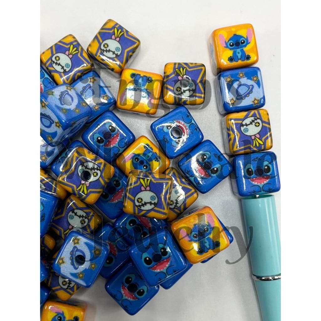 A collection of blue acrylic beads with a character design, alongside a beadable pen.

