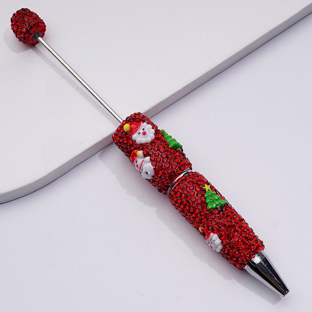 Decorative pen with red and green gemstones on a white background


