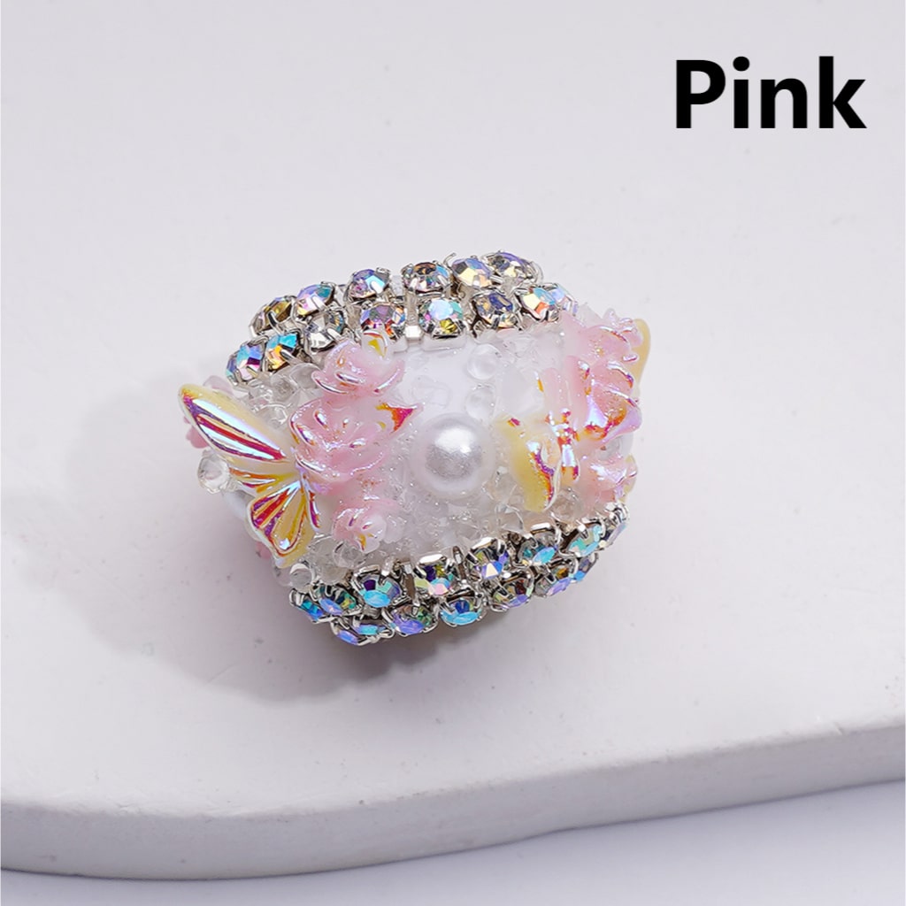 Decorative ring with pink and white design on a light gray background


