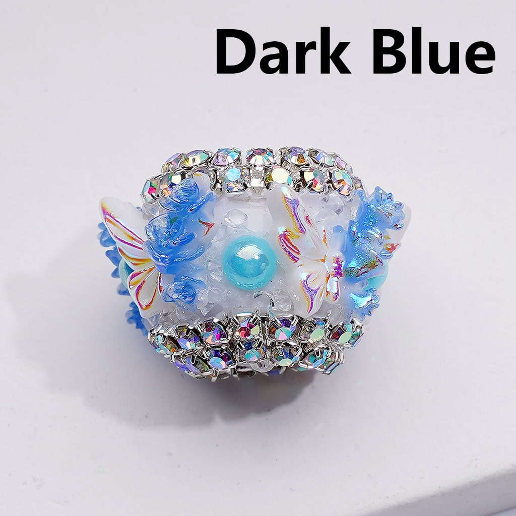 Decorative dark blue item with floral designs and rhinestones on a white background

