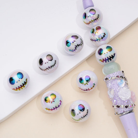 A collection of white UV coating acrylic beads with jack face prints, displayed on a surface alongside a pen for scale.

