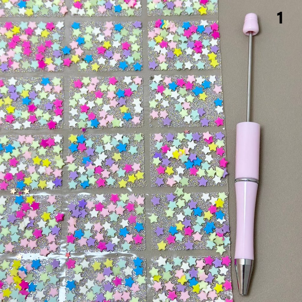 Sheet of colorful star-shaped stickers with a pink tool on a gray background


