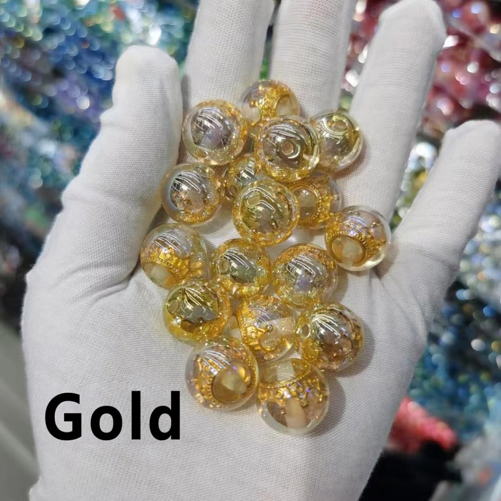 Hand holding gold marbles with a colorful blurred background

