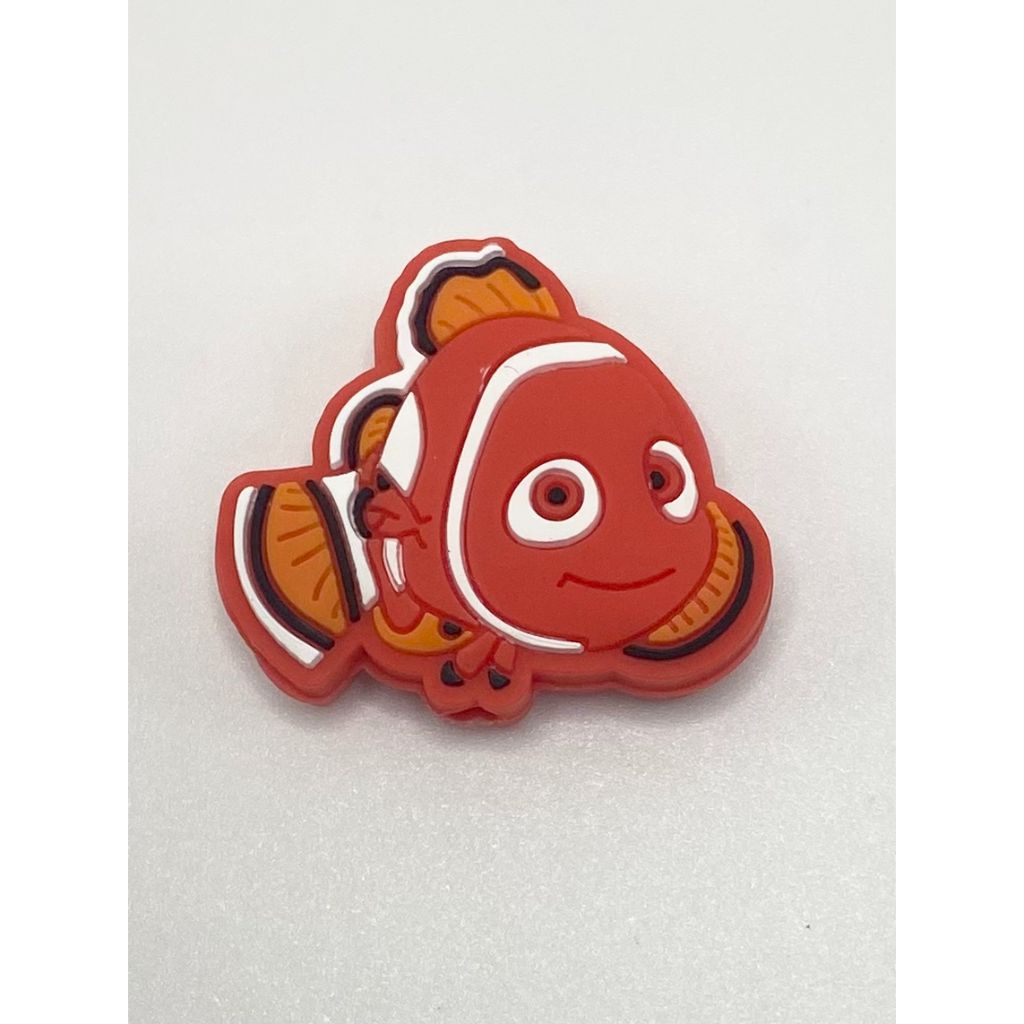 A red silicone bead in the shape of a goldfish with a white spot on its face and orange fins.

