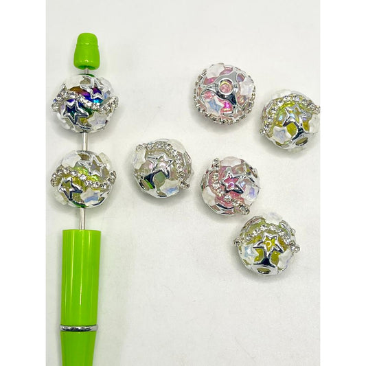 A collection of multicolored acrylic beads with a star shape at their center, displayed alongside a green pen for scale.

