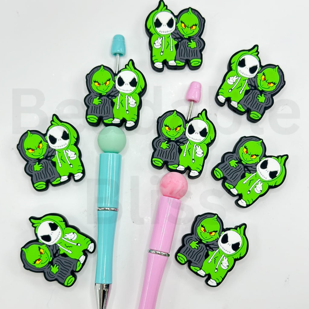 Two pens with green character charms on a white background

