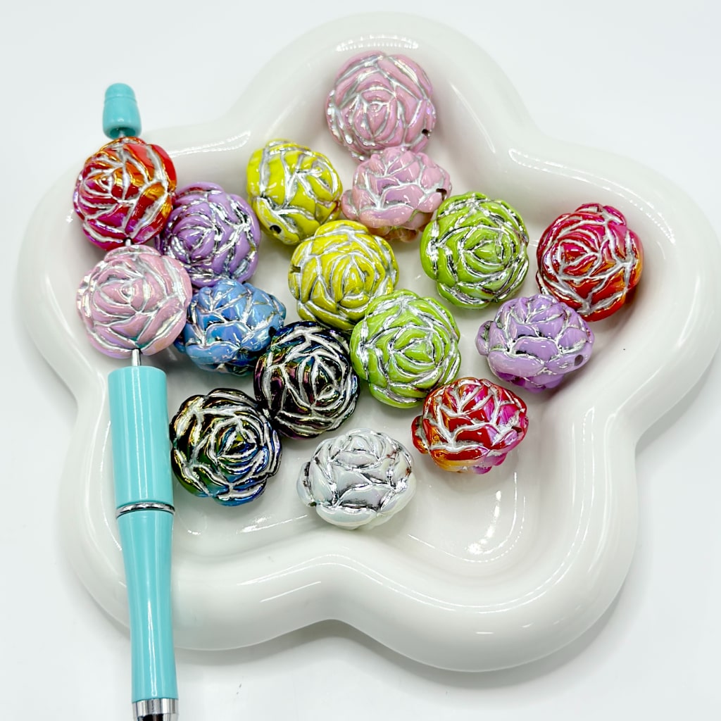 A collection of rose flower shaped acrylic beads in various solid colors displayed on a white surface.

