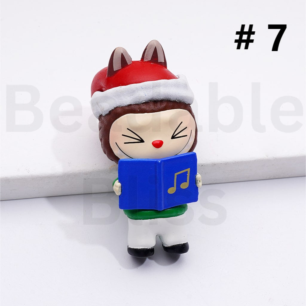 Small figurine of a character wearing a red hat and holding a blue book with music notes on a white background.

