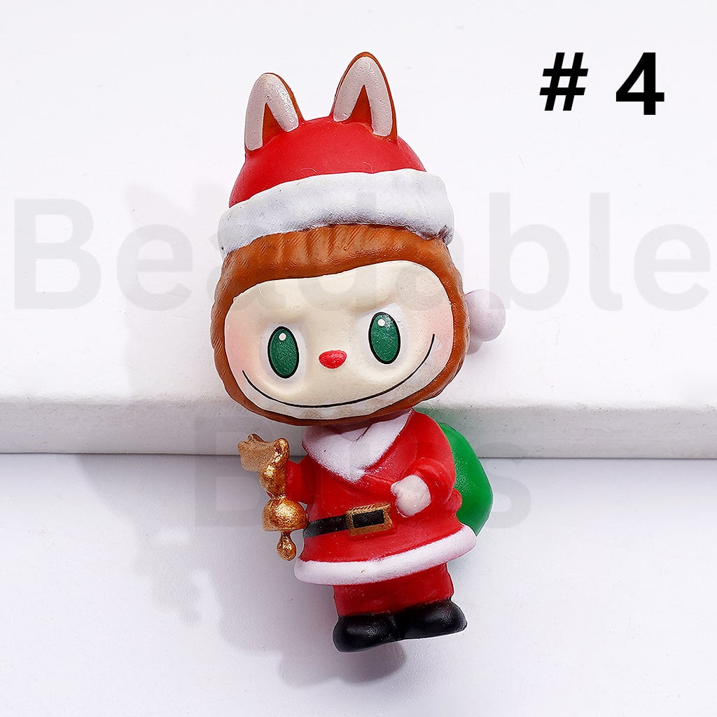 Small figurine of a character in a Santa outfit with a bell and green bag on a white background.

