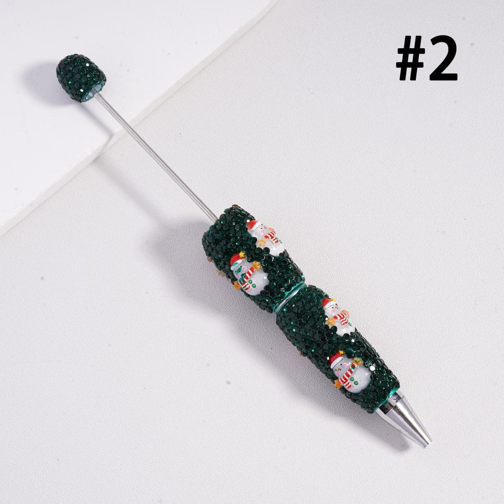 Decorative pen with green and black gemstones on a white background

