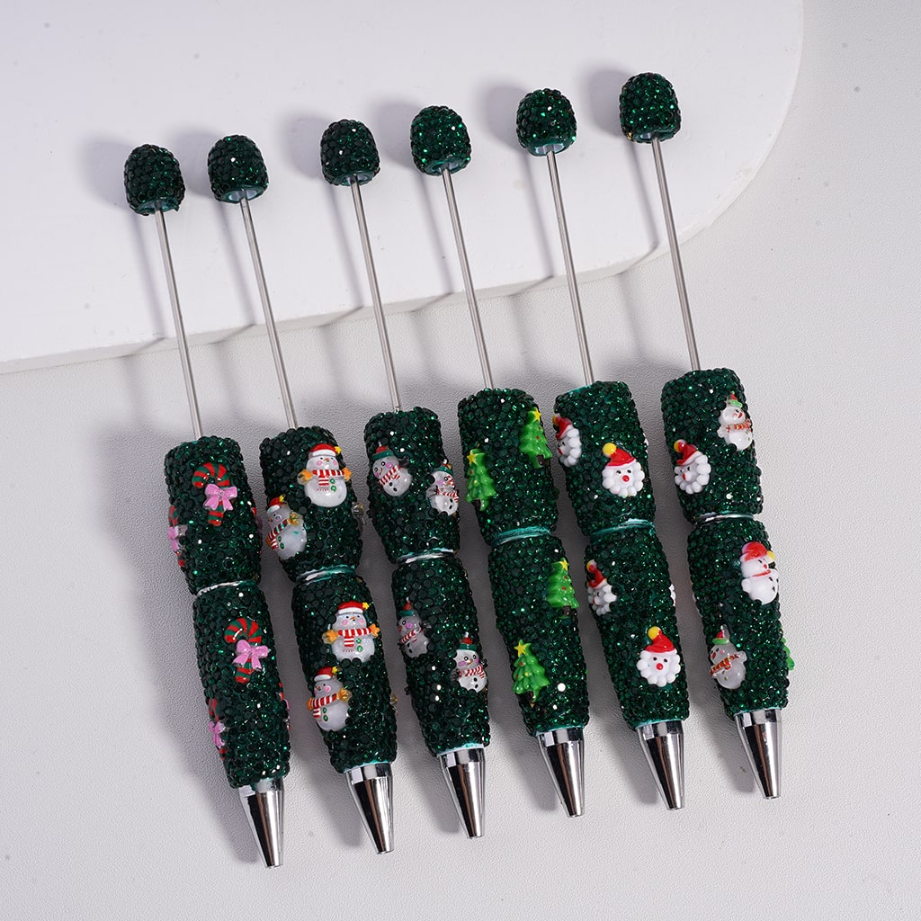 Set of Christmas-themed pens with glittery green accents on a white background

