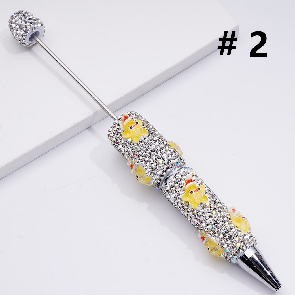 Decorative pen with rhinestones and small figures on a white background

