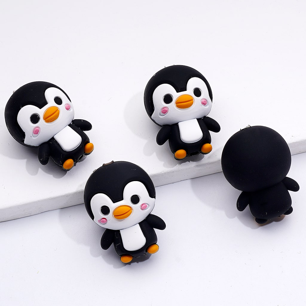 Three cartoon penguin figurines on a white surface

