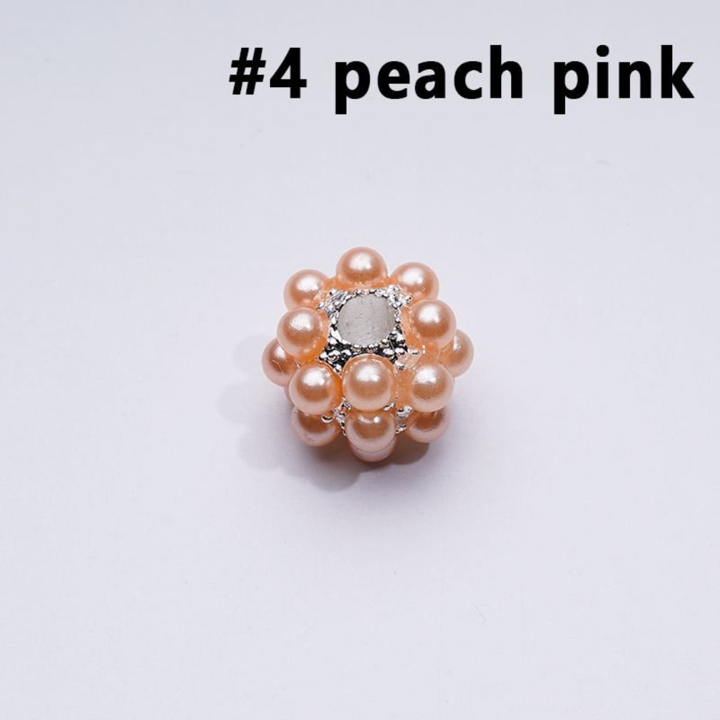 Decorative item with peach pink pearls and a silver center on a light gray background

