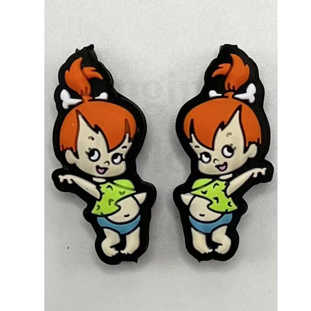 Cartoon character earrings with orange hair and green shirt on a white background

