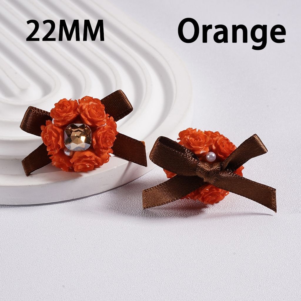 Orange floral hair clips with brown ribbons on a white background
