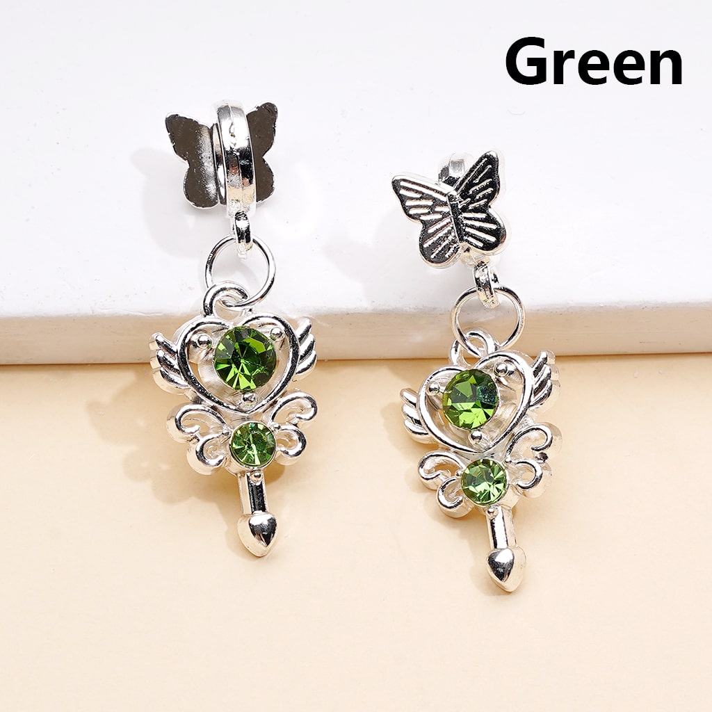 Silver butterfly earrings with green gemstones on a beige surface.

