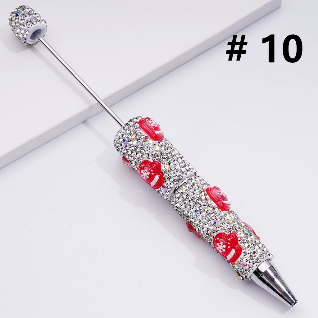 Decorative pen with red heart designs and clear gemstones on a white background


