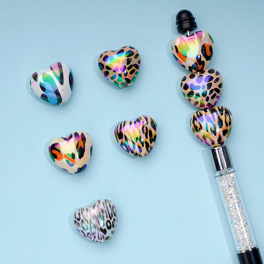Decorative pen with leopard print heart-shaped accents on a light blue background

