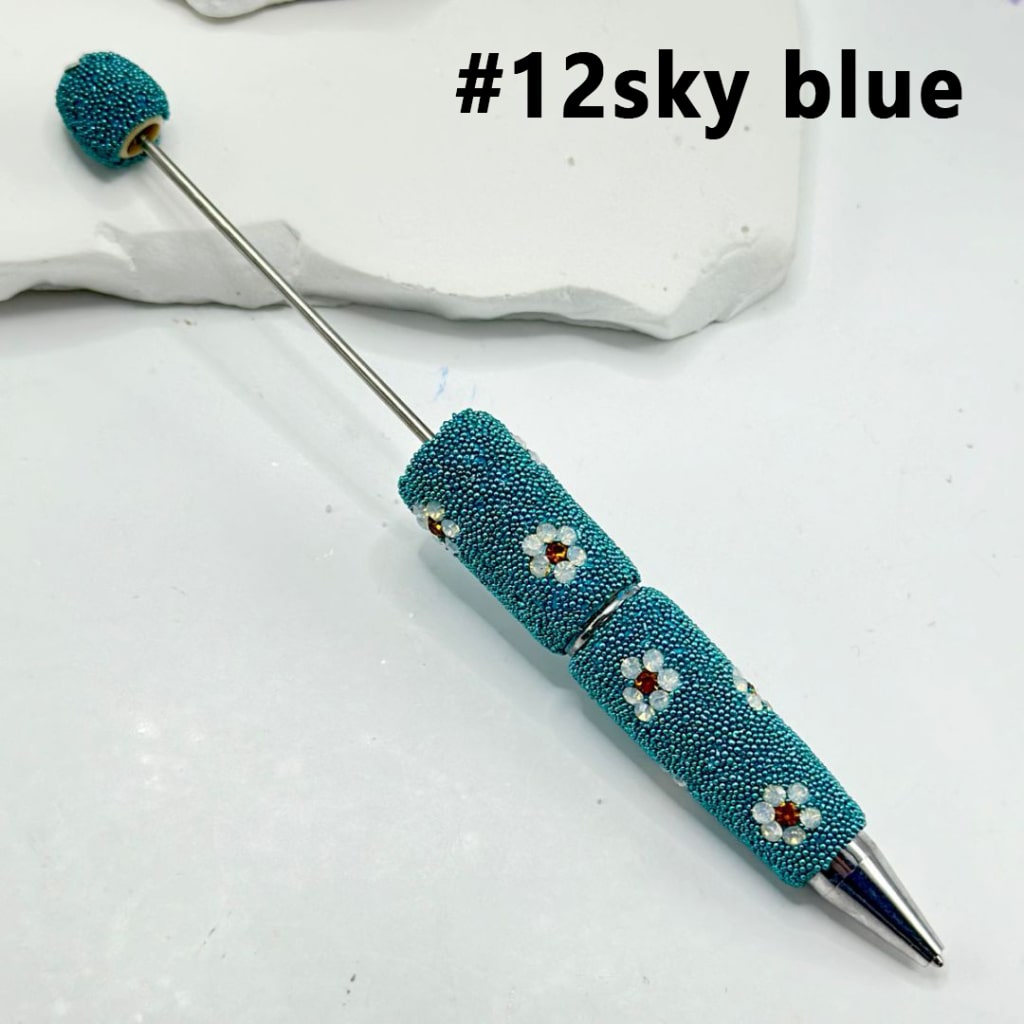 Decorative pen with blue bead accents on a white background

