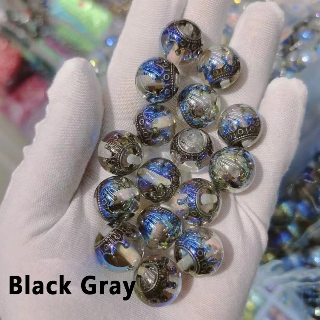 Hand holding a collection of black and gray beads with a blurred background

