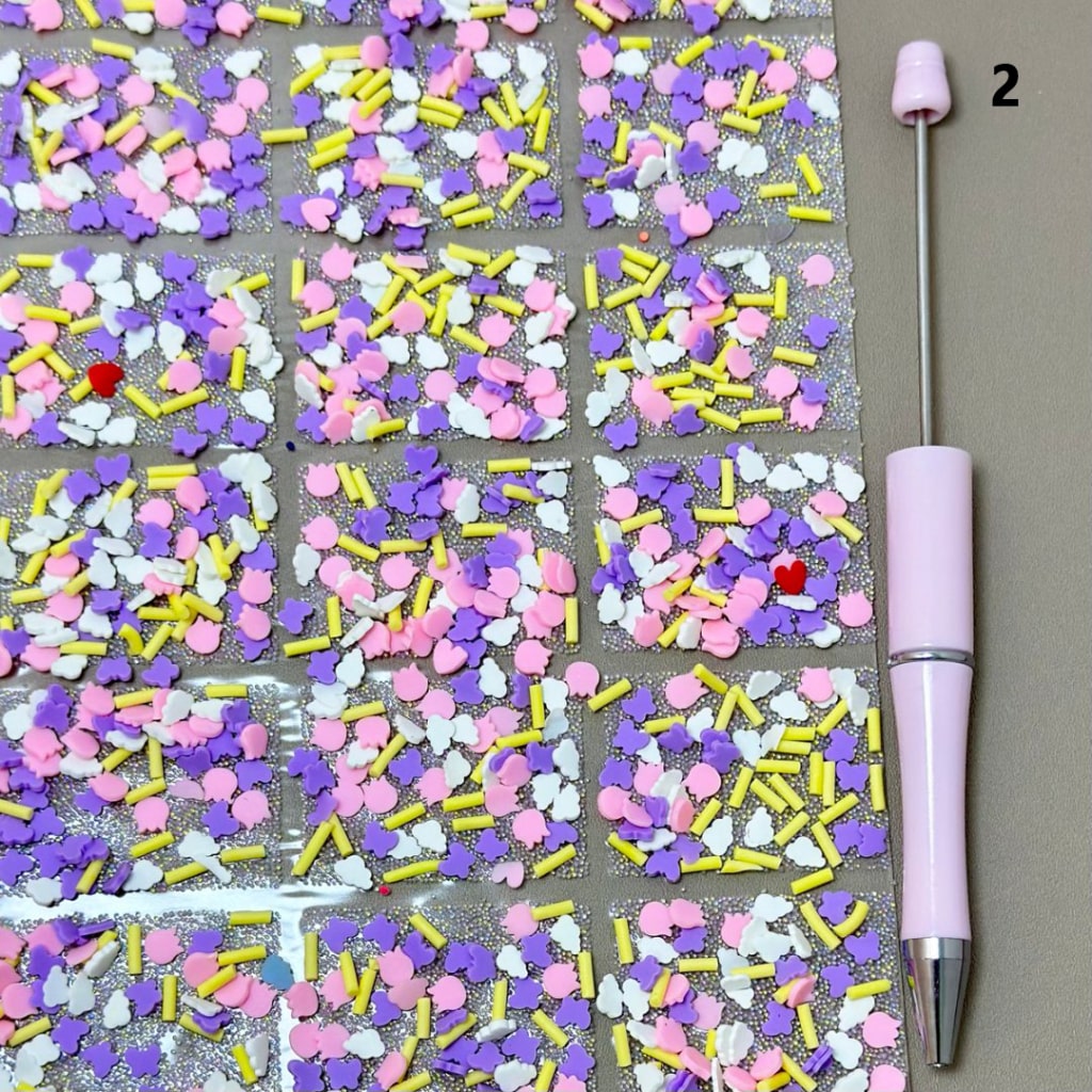 Colorful sprinkles on a grid with a pink tool next to it

