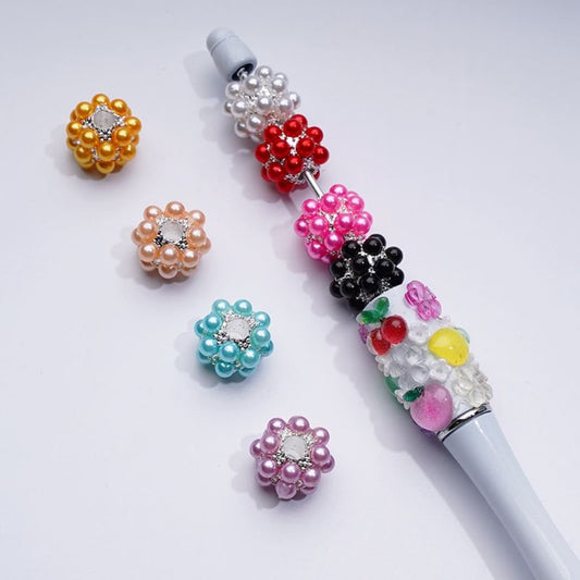 Decorative pen with colorful bead attachments on a white background

