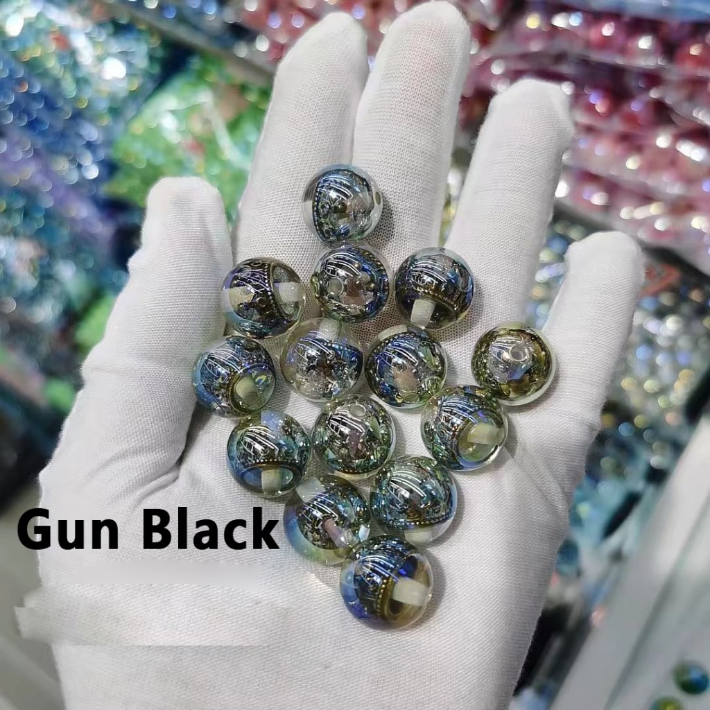 Hand wearing a white glove holding gun black marbles with a colorful blurred background.

