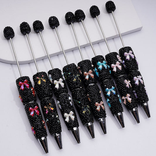 Set of decorative pens with black beads and colorful bows on a white surface

