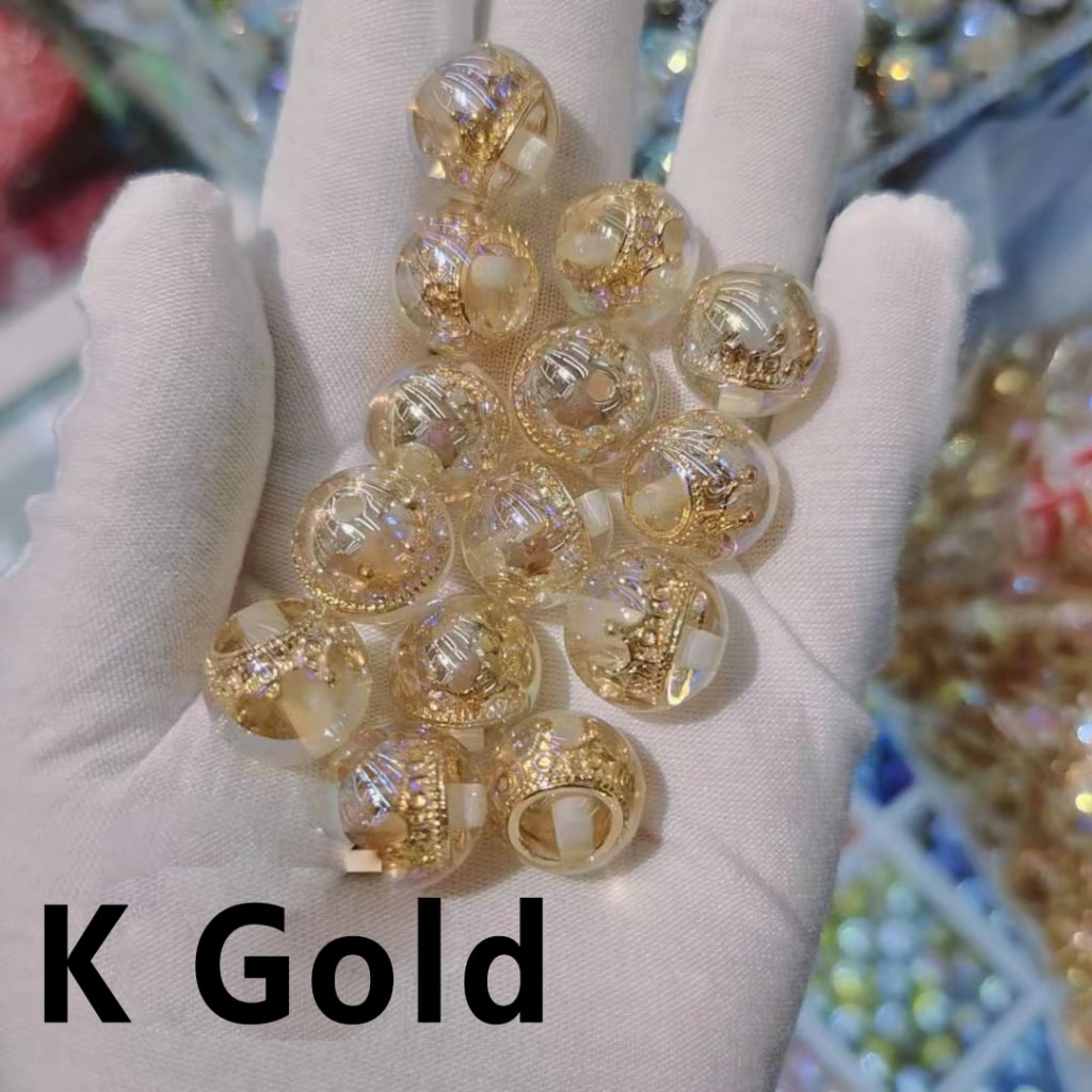 Gold beads held in a hand wearing a white glove with 'K Gold' text.

