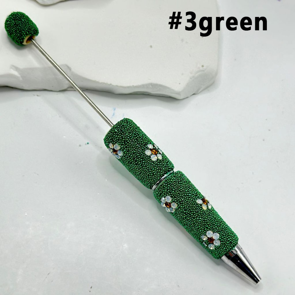Decorative pen with green bead design on a white background

