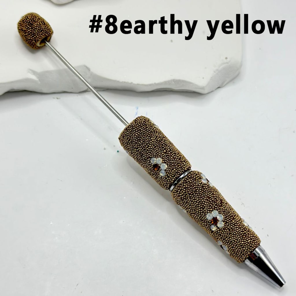 Decorative pen with textured grip and decorative elements on a light background, labeled '#8earthy yellow'.

