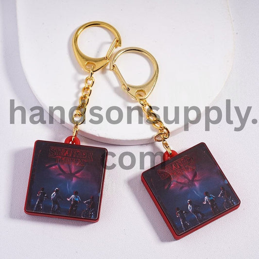 Pendant Charm Flat Square Shape Metal Keychain with Gold Lobster Clasp Red Background & Dark Fantasy Character Design Horror Style