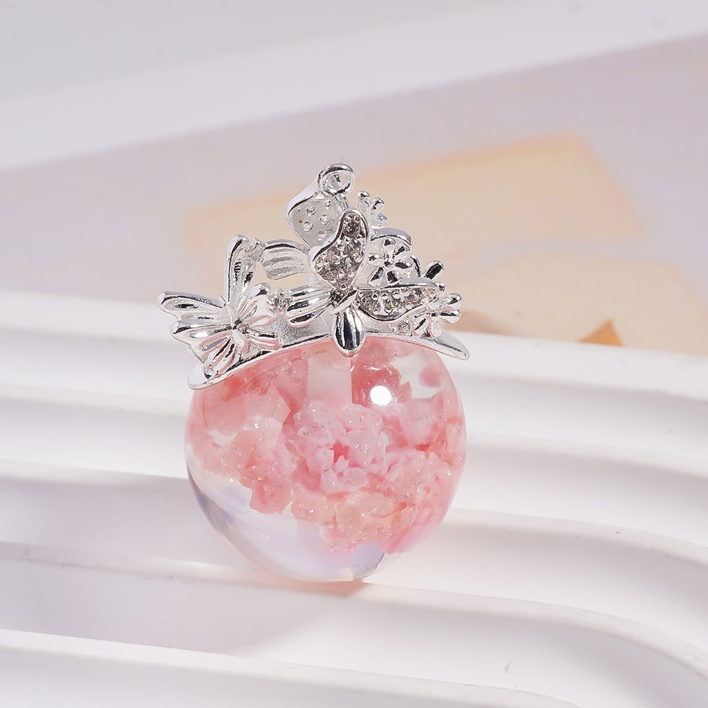 Pink marbled pendant with silver butterfly design on a white background


