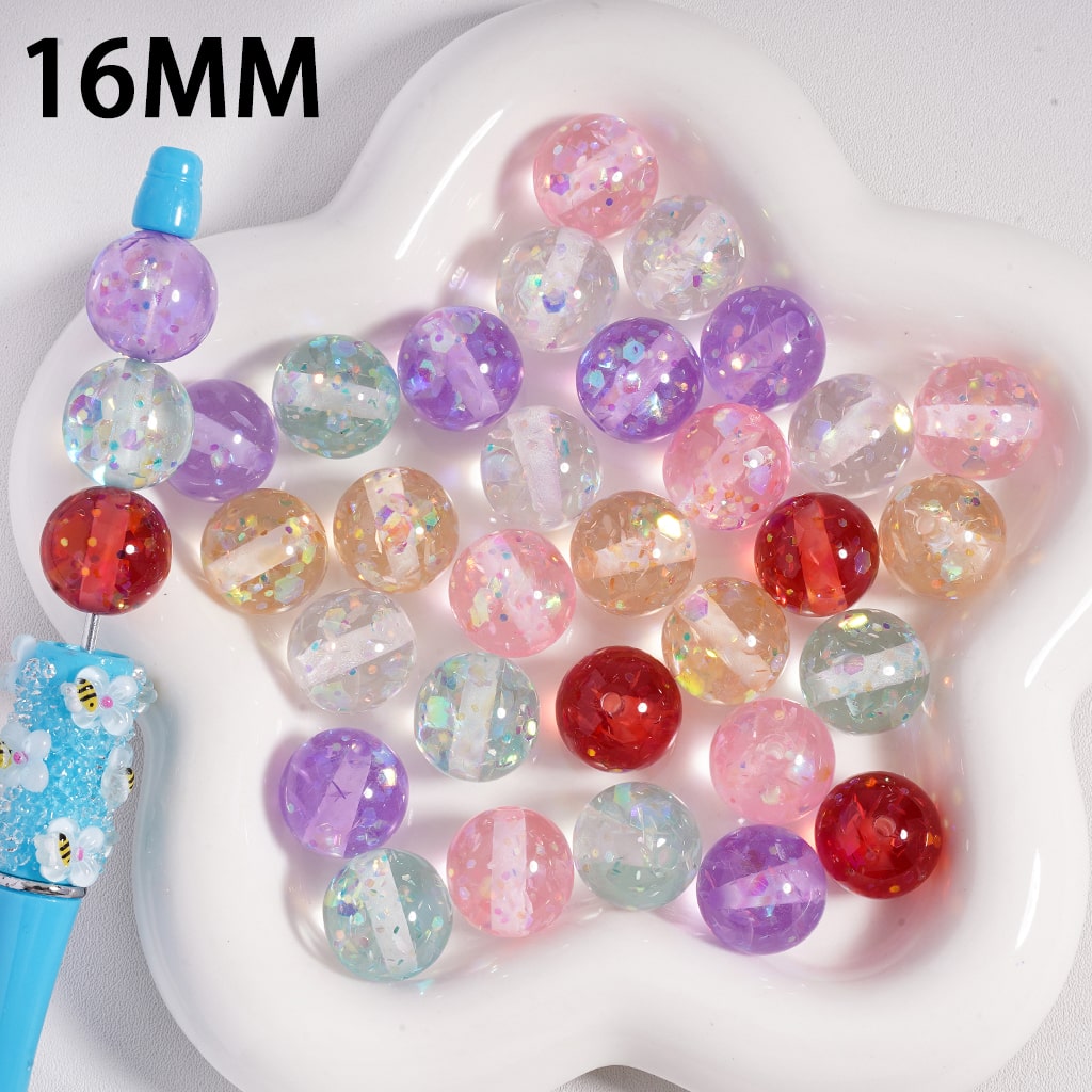 Colorful glittery beads on a white heart-shaped tray with '16MM' text.

