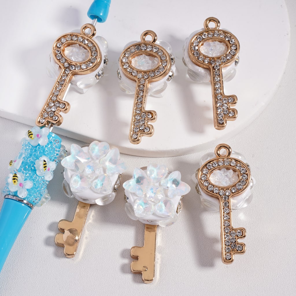 Decorative key-shaped charms with gemstones on a white background

