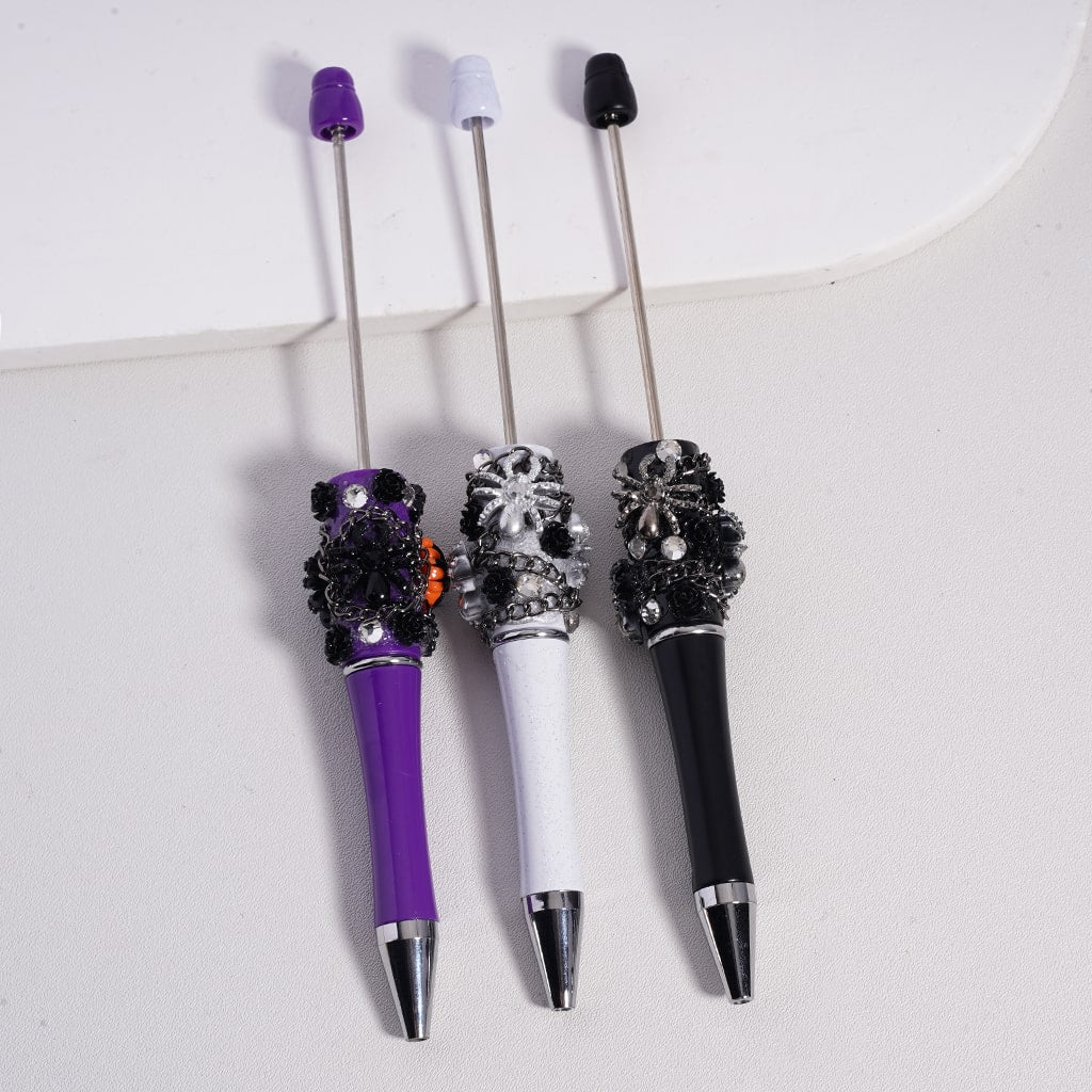 Three decorative pens with gemstone accents on a white background

