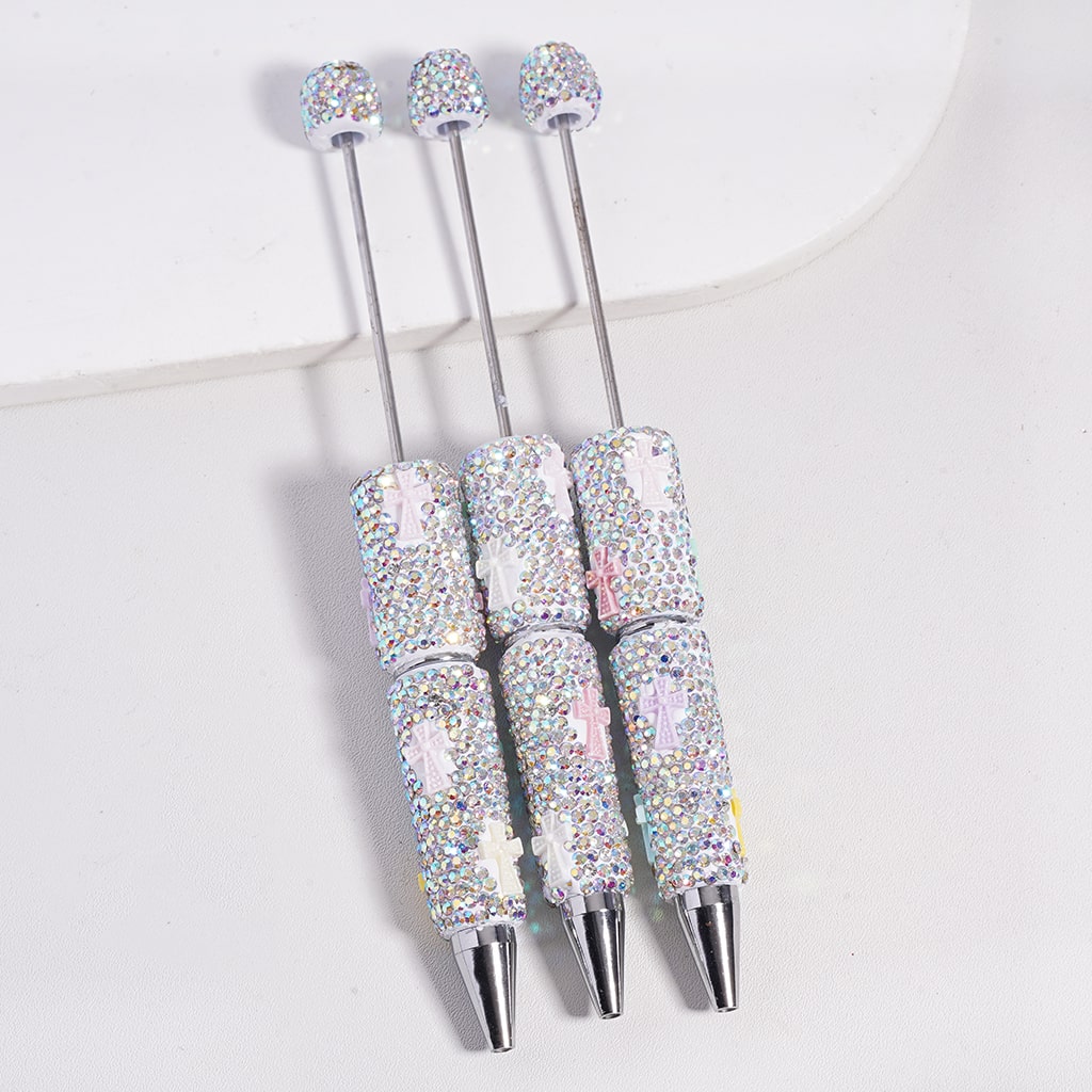 Three decorative pens with glittery accents on a white background

